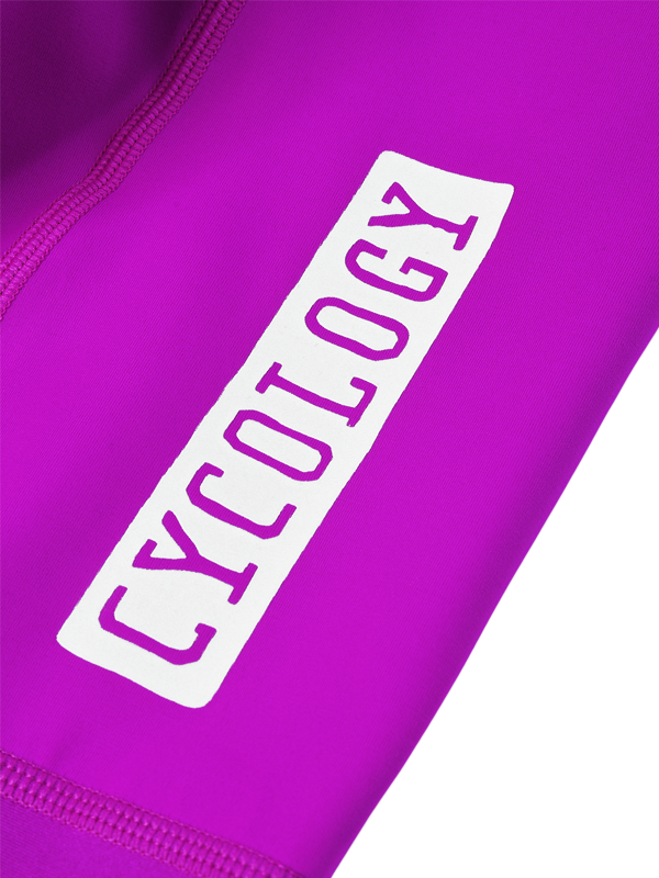 Close-up of a bright purple athletic garment with a white rectangular patch featuring the word 'CYCOLOGY' in purple lettering.