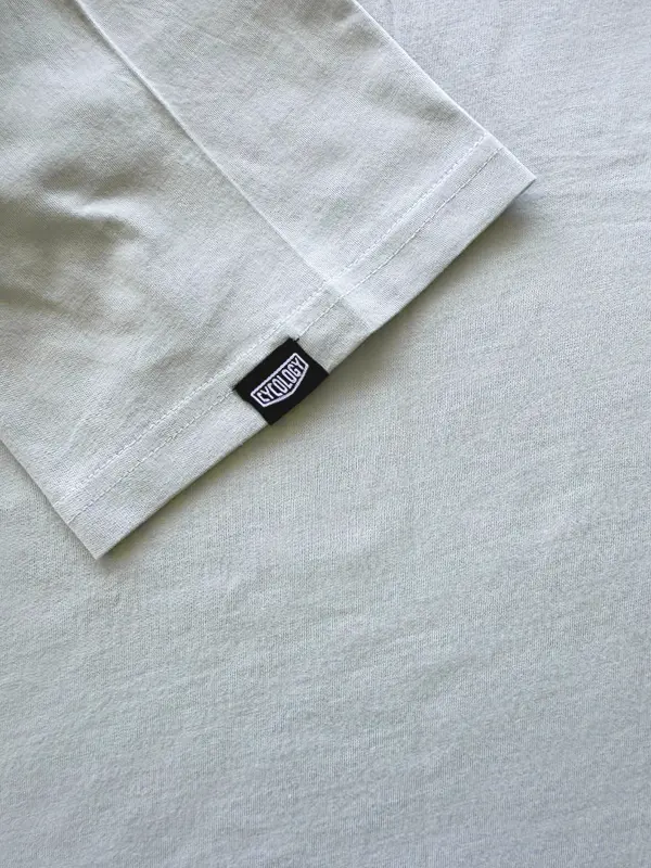 Light gray t-shirt with a brand label on a matching gray background
