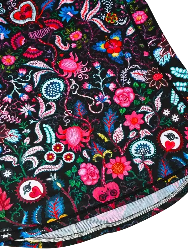 Vibrant floral cycling shorts with bold pink, blue, and red patterns on black fabric, featuring bike and heart motifs.