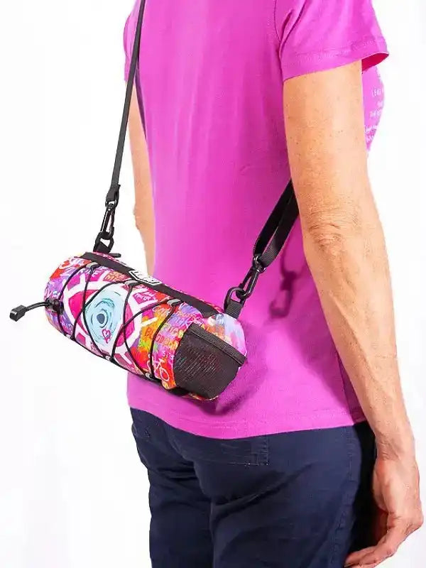 Colorful cycling waist bag with floral print, worn crossbody by person in pink shirt