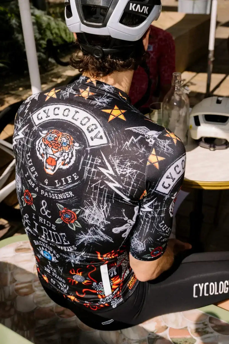 Men's cycling jersey with bold tiger graphic, stars, and 'Cycology' branding, worn with Kask helmet and matching bib shorts.