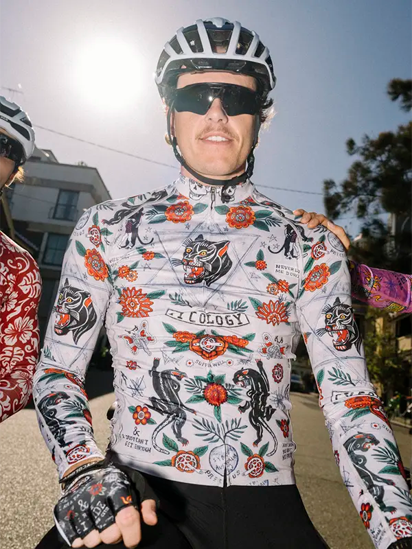 Cyclist wearing a colorful cycling jersey with a tiger and floral design, helmet, and sunglasses.