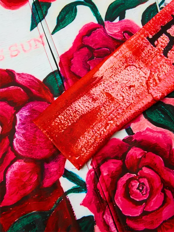 Red textured object on a floral background with pink roses and green leaves.