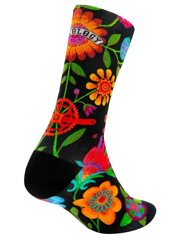 A single crew cycling sock with a black background and a vibrant, multicolored floral pattern, shown against a plain white background.