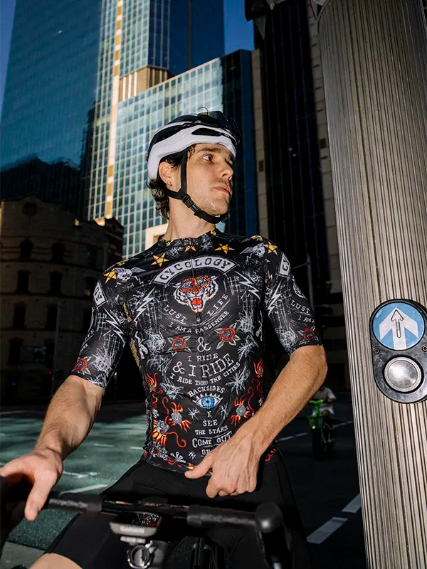 Person wearing a black men's colorful cycling jersey with a cityscape background