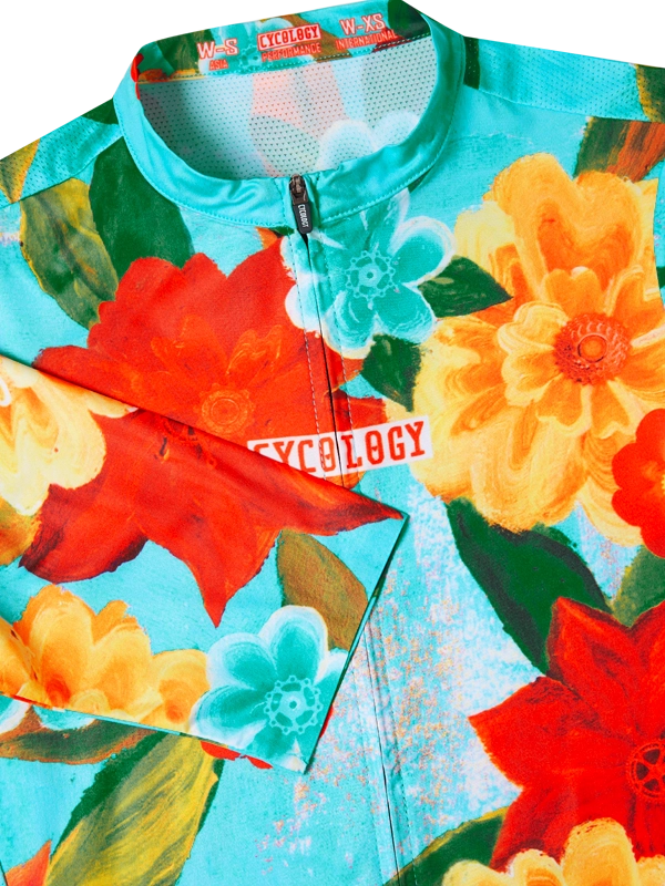 Colorful women's floral-patterned cycling jersey with 'Cycology' branding on a aqua background