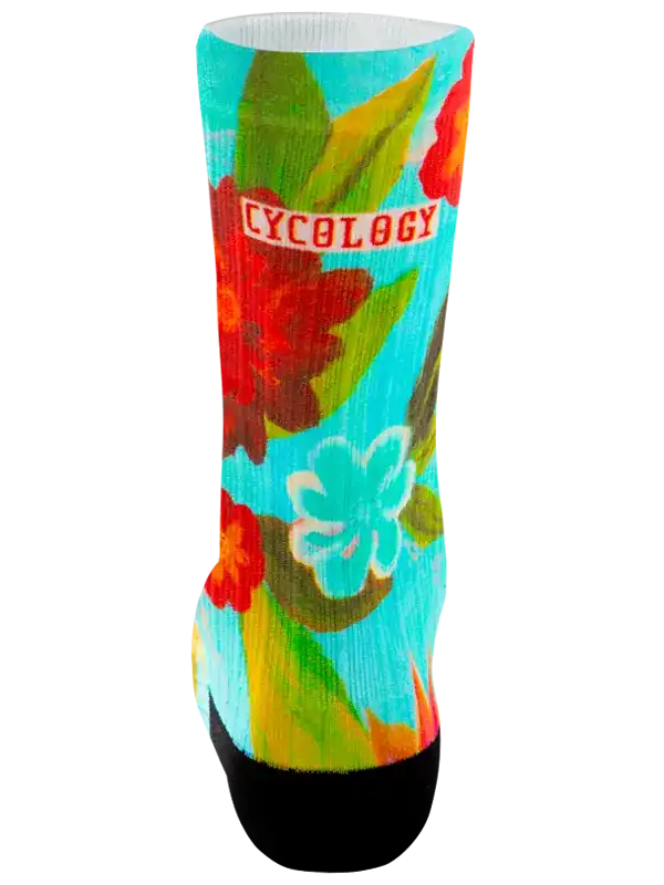 A single crew sock with a vibrant tropical floral print on a turquoise background, featuring red and light blue flowers, green leaves, and a black toe and heel. The word 'CYCOLOGY' is printed in red across the upper calf.