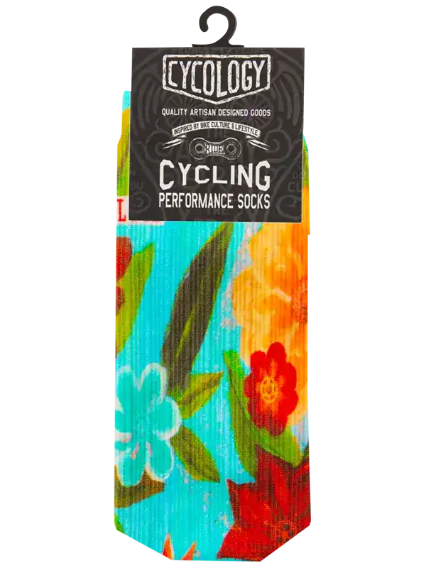 A pair of colorful cycling performance socks in tropical floral print, hanging from a black hanger with a black header card that reads 'CYCOLOGY CYCLING PERFORMANCE SOCKS'. The socks feature a bright turquoise, orange, red, and green pattern on a white background.