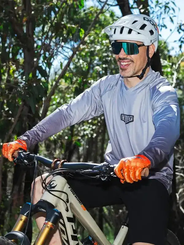 Man cycling in forest wearing performance cycling jersey, helmet, and gloves