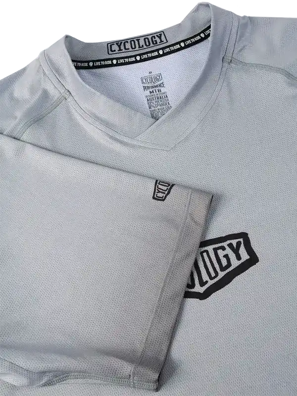 Grey cycling jersey with black Cycology logo, breathable mesh fabric, V-neck design for men or women