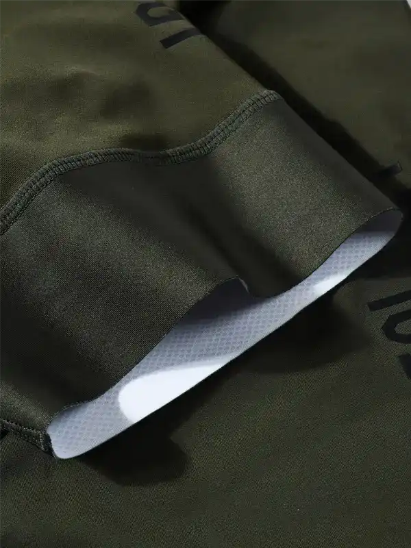 Close-up of an olive green cuff detail, showing a white inner lining and dark printed lettering on the fabric.