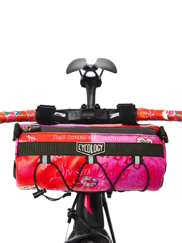 Bicycle handlebar with a pink and red bike bag labeled 'Cycology' 