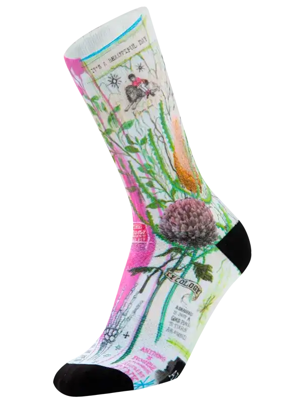 A single crew cycling sock with a colorful botanical and vintage-style print, featuring pink, green, blue, and orange illustrations on a white base, with black toe and heel sections.