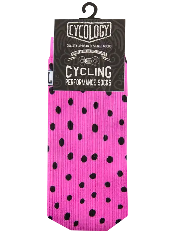 A pair of bright pink cycling performance socks with black polka dots, packaged on a black hanger card labeled 'Cycology'.