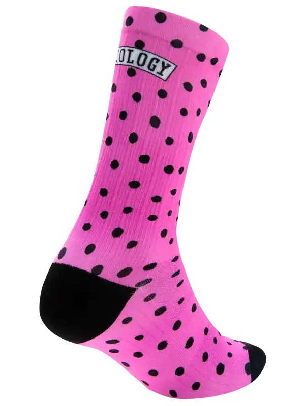 A single bright pink crew cycling sock with a black polka dot pattern, black toe and heel, and a white ribbed cuff, shown on a plain white background.