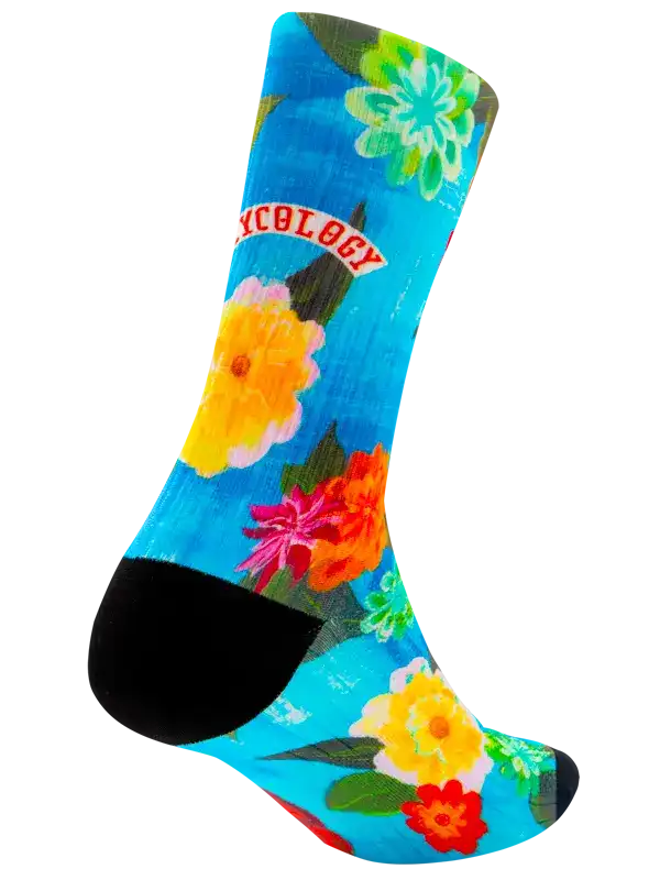 A single crew cycling sock with a bright tropical floral print on a turquoise blue background, featuring orange, red, yellow, and white flowers with green leaves, finished with black toe and heel sections.