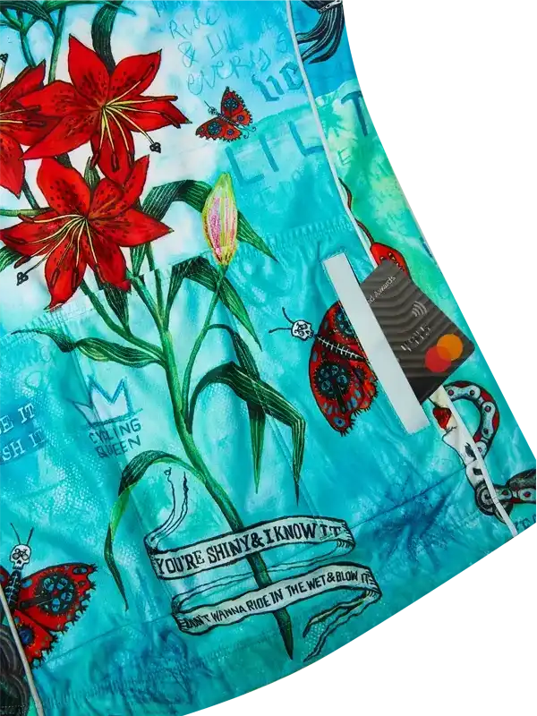 Women's cycling shorts with vibrant red lilies, butterflies, and bold text on teal fabric