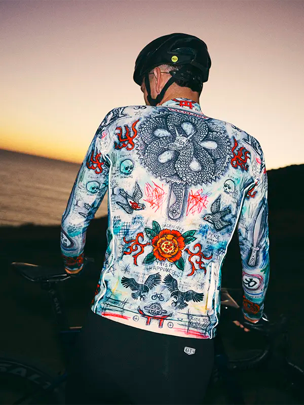 Person wearing a colorful cycling jersey with intricate designs against a sunset background.