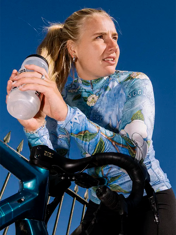 Woman in a blue  women's long sleeve cycling jersey with floral and bird design