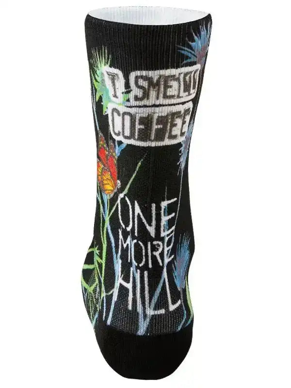 Black cycling sock with 'I Smell Coffee One More Hill' text, butterfly, and floral graphics for riders