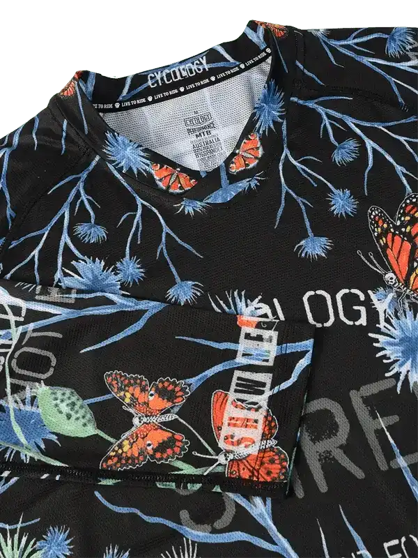Black cycling jersey with butterfly and blue branch print, featuring breathable fabric and brand tag