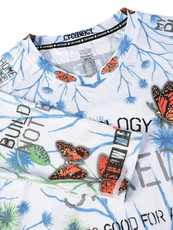 Men's cycling jersey with butterfly print, blue floral design, and 'BUILD NOT BREAK' text on white fabric