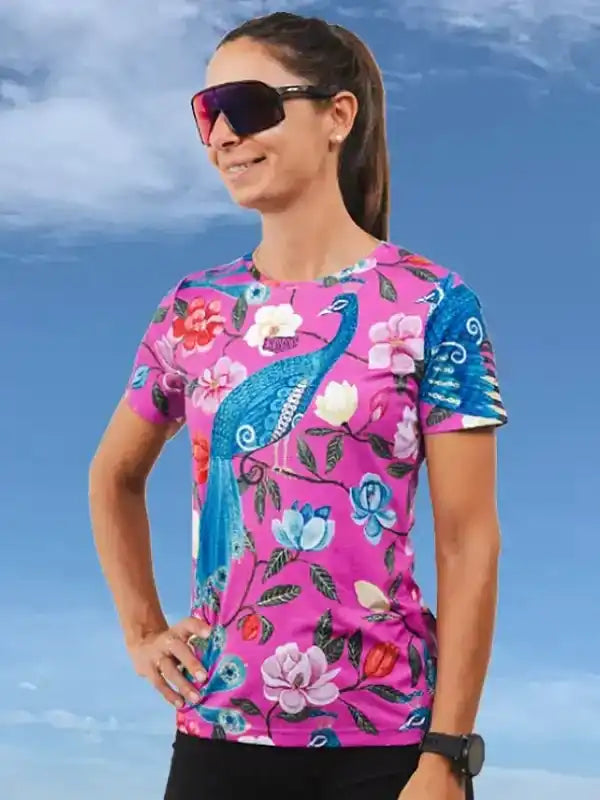 Woman wearing vibrant pink floral cycling jersey with peacock design, ideal for women's cycling apparel