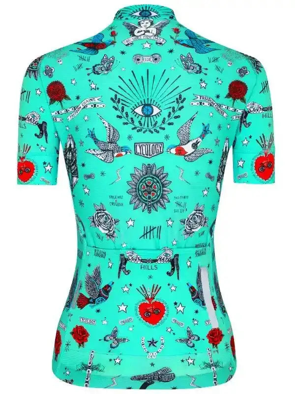 Women's turquoise cycling jersey with tattoo-style graphics, roses, birds, and stars for road biking