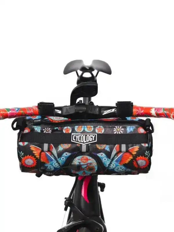 Colorful butterfly-patterned cycling handlebar bag with Cycology logo, mounted on bike handlebars