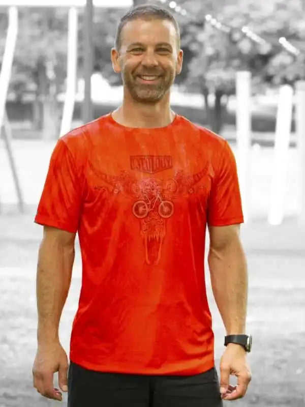 Man wearing red cycling t-shirt with skull and bike graphic, ideal for men's cycling apparel